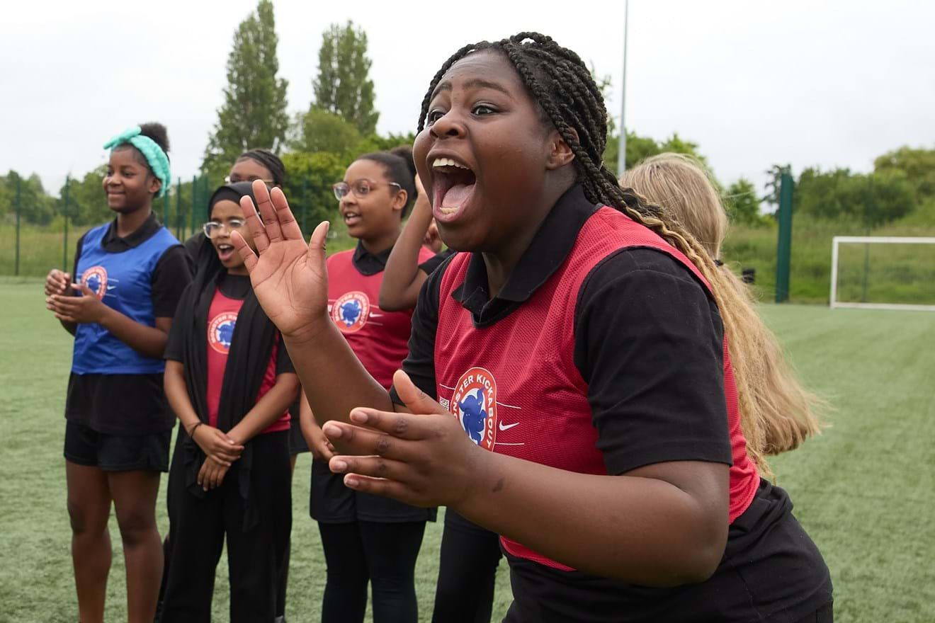 Group of girls cheering on a team on a sports field