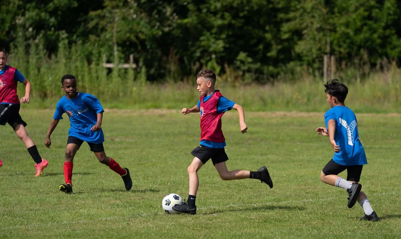 Four boys playing football on a field