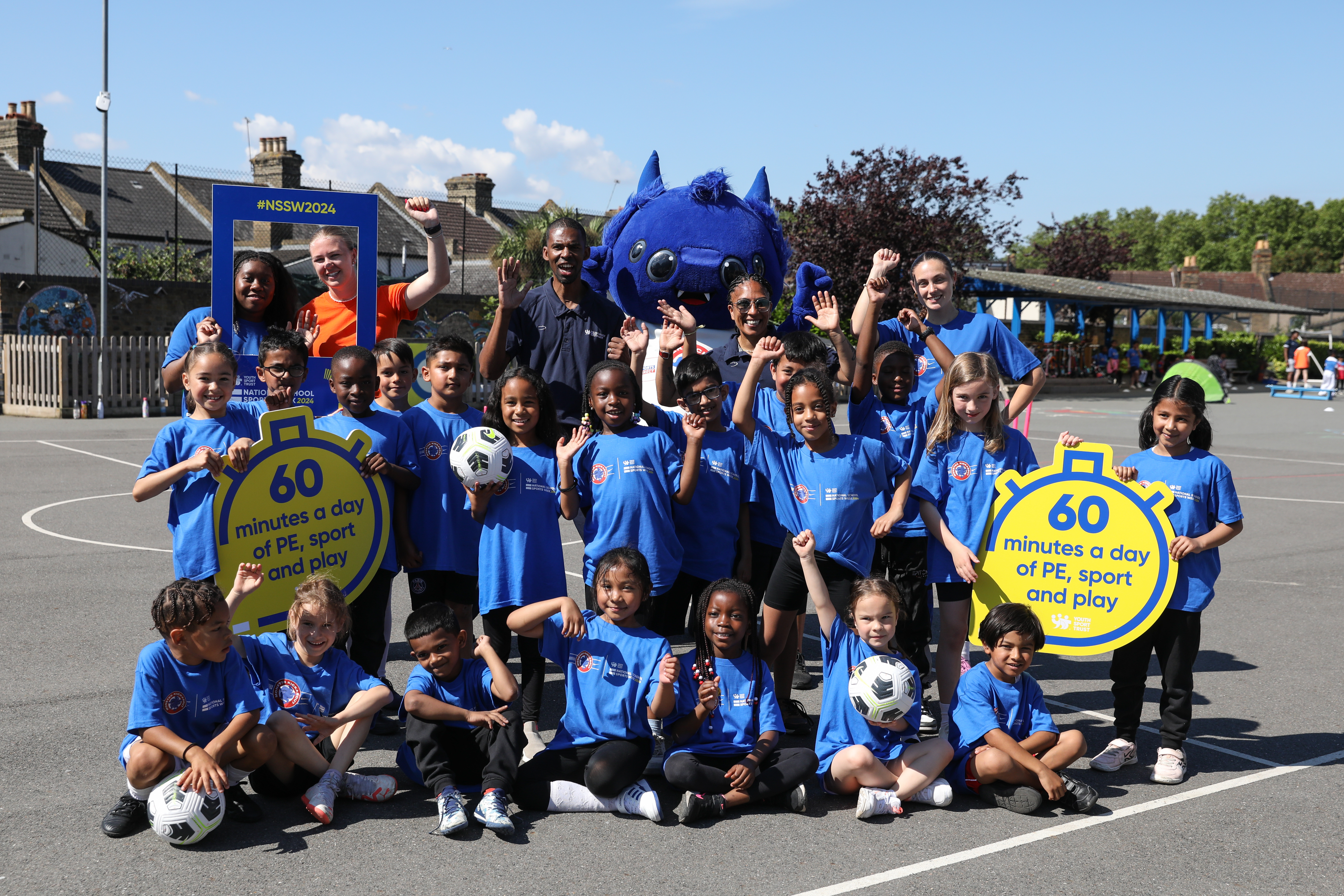 Big group of children and athletes cheering and waving at camera