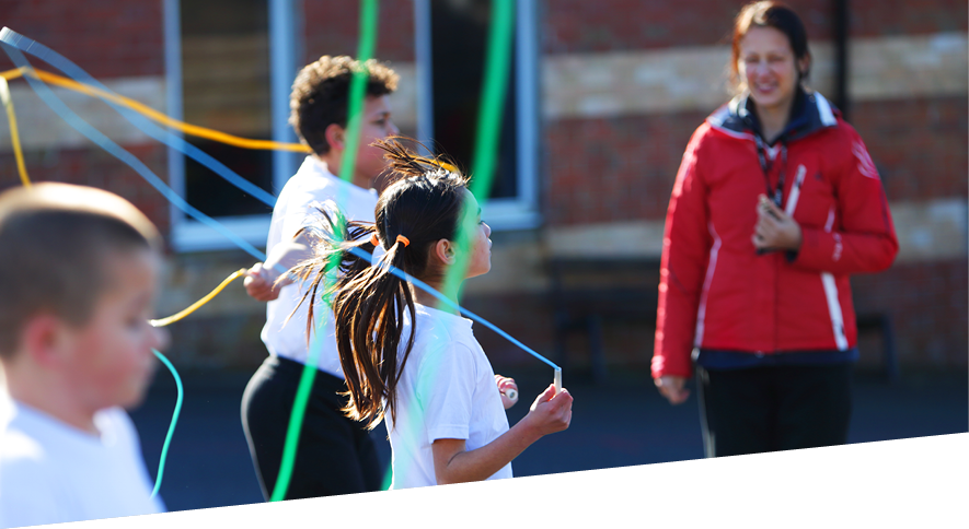 Group of young people and teacher taking part in activity with ribbons in an outdoor playground