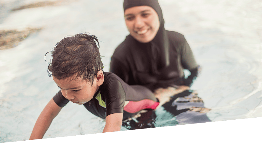 Mother helping young boy learn to swim