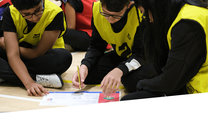 Group of young people sat on the floor working on a problem together